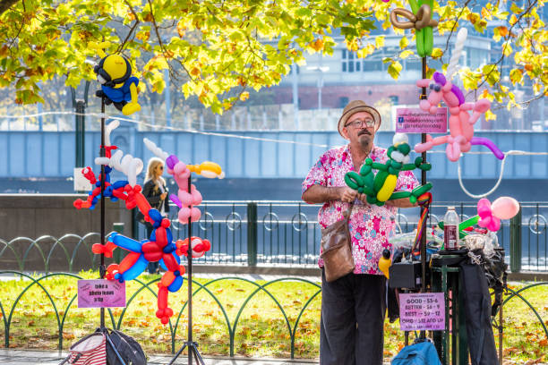 A street performer is making and selling balloon animals Melbourne, Victoria, Australia, April 14th 2019: A street performer is making and selling balloon animals at Southbank next to the Yarra River on a sunny day circus clown carnival harlequin stock pictures, royalty-free photos & images