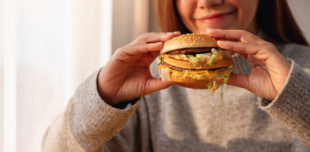 istock a young woman holding and eating hamburger 1300608160