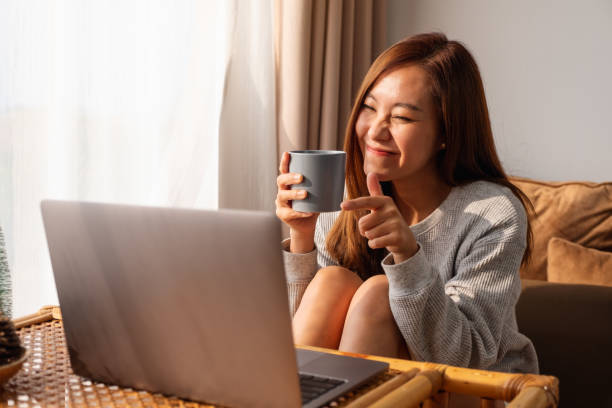 istock A beautiful young asian woman using laptop computer for video call while sitting and drinking coffee at home 1300608171