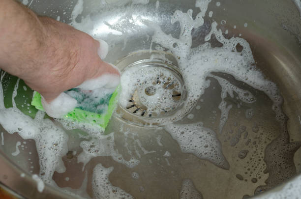 istock A man's hand washes the kitchen sink with a dish sponge. 1300609188