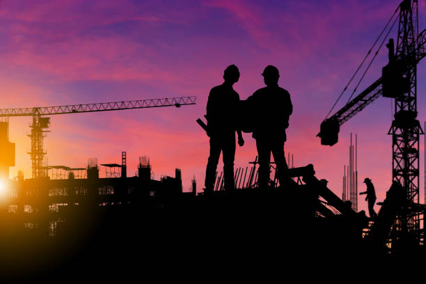 istock Silhouette of Engineer and worker checking project at building site background, construction site at sunset in evening time 1300610851