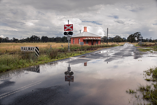 Railway crossing station in rural NSW Australia. Reflection in road puddles after some heavy rain.
