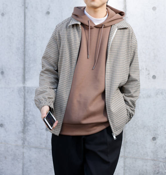 istock Young man holding a smartphone in front of a concrete wall 1300618503