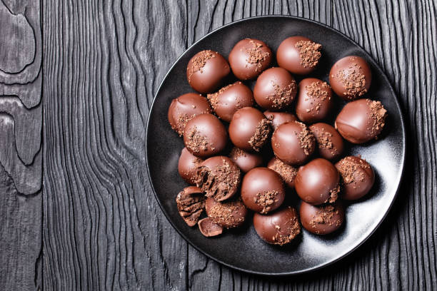 istock chocolate truffles on a black plate on a black textured wooden table, horizontal view from above, flat lay 1300619801