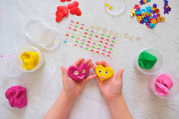 istock Child playing with colorful modeling clay, making hearts for valentines day 1300621347
