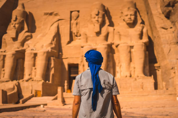 młody turysta w niebieskim turbanie patrząc na świątynia abu simbel w południowym egipcie w nubii nad jeziorem nasser. świątynia faraona ramzesa ii, podróżny styl życia - lake nasser zdjęcia i obrazy z banku zdjęć