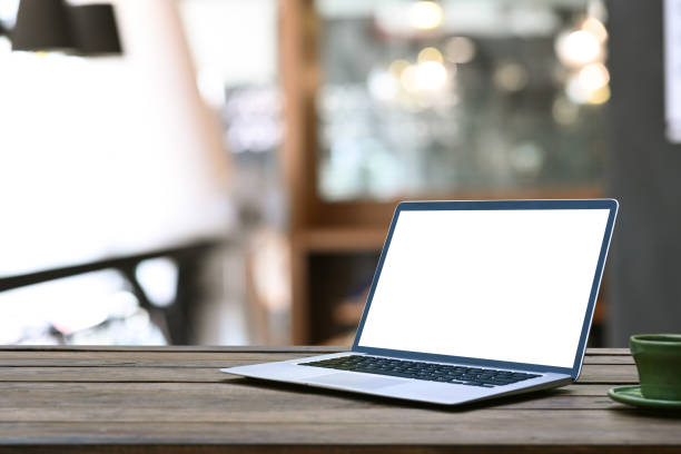 istock Mock up laptop with blank screen on wooden table in coffee shop. 1300627187