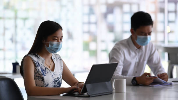 istock Two business colleagues in protective mask working together on new project in modern office. 1300627240
