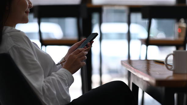 istock Happy young woman using mobile phone while relaxing at coffee shop. 1300627296