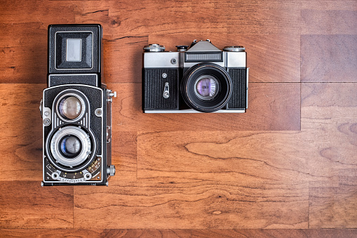 an old medium format twin lens reflex camera and an old 35mm reflex camera, seen from above horizontal format with copy space