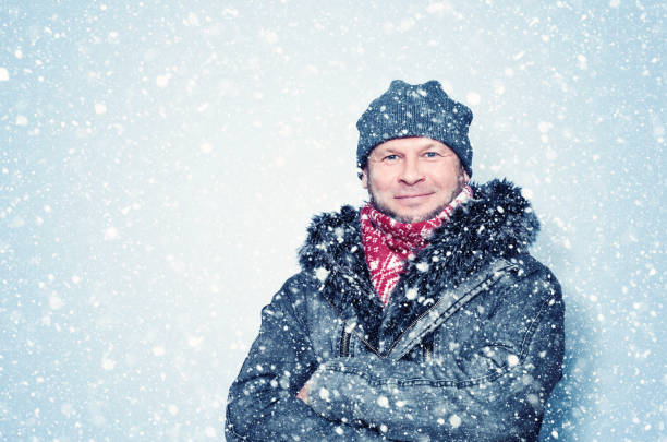 istock Happy smiling bearded man in winter clothes, it is snowing around background. 1300628599
