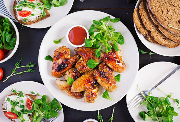 istock Grilled chicken wings. Baked chicken wings on wooden table. Table setting. Top view, flat lay, overhead 1300629909