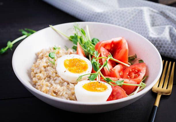 istock Breakfast oatmeal porridge with boiled egg, cherry tomatoes and microgreens. Healthy balanced food. 1300629942