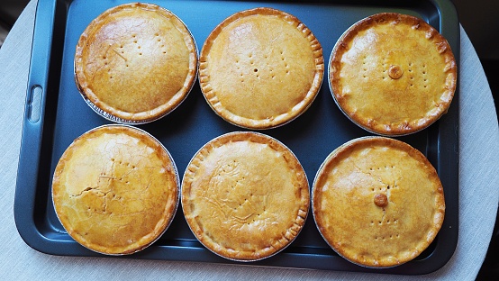 Close up on pork, beef and chicken pies on cooking tray. Pastry background.