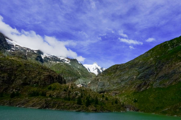 istock wonderful high mountains with blue sky and a water in the front 1300635593