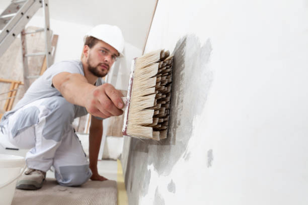 istock construction worker painter man with protective helmet, brush in hand restores and paint the wall, inside the building site of a house, closeup 1300640600