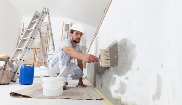 istock construction worker painter man with protective helmet, brush in hand and buckets of products to restore and paint the wall, indoor the building site of a house 1300640720