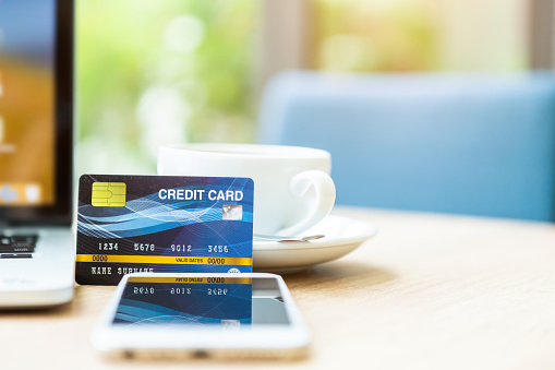 Credit card of laptop computer,smartphone and coffee cup on wooden table of In the coffee shop background,Online banking Concept