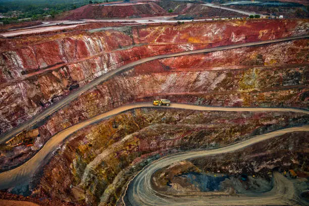 Yellow truck drives along a winding path inside an open cast mine in New South Wales, Australia.