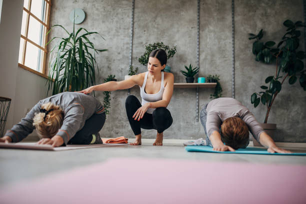 istock Yoga instructor assisting women on yoga class 1300650604