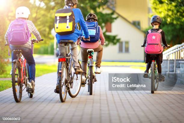 Children With Rucksacks Riding On Bikes In The Park Near School Stock Photo - Download Image Now
