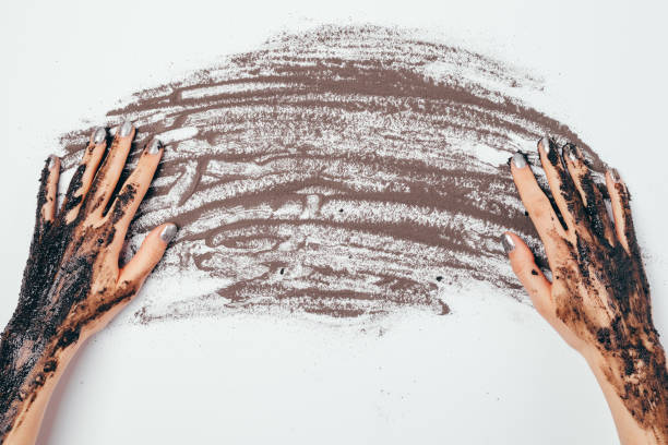 istock Female hands with applied cosmetic scrub mask sprinkled black clay 1300653965