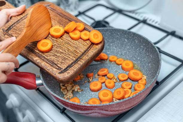 Roasting carrots in a deep wok pan. Frying for soup or cooking vegetable stew .