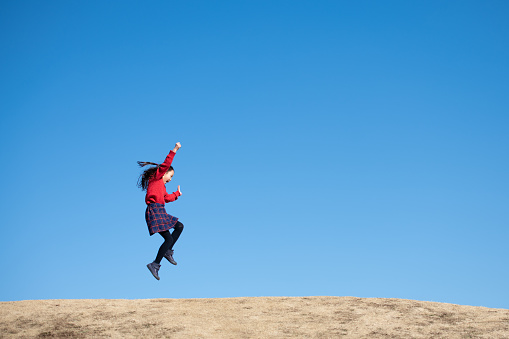 Girl jumping under the blue sky