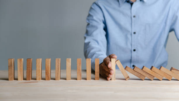 uomo d'affari che ferma il concetto di effetto domino in legno per la pianificazione, il rischio e la strategia negli affari. - change changing form organization leadership foto e immagini stock