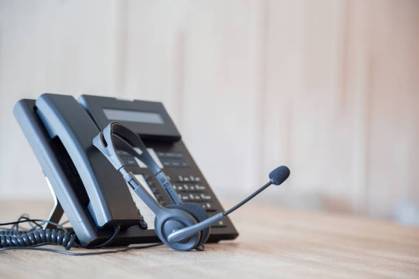 istock Communication support, call center and customer service help desk. VOIP headset on telephone keyboard. 1300658030