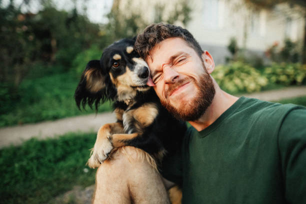 istock Young man is playing with a dog and do selfie 1300658239