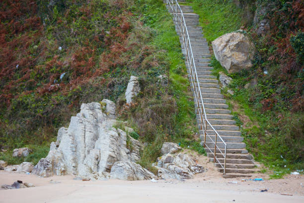 Stairs with handrails leading up a rock.Stairs with handrails leading up and right to the top of an orange rock, viewpoint, blue sky, some clouds, no adequate access for disabled people
