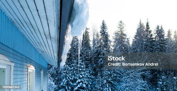 Snow And Icicles On The Roof Of A Wooden House Spring Season Stock Photo - Download Image Now