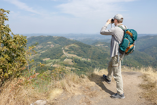 Man taking a rest after a hike and looking through binoculars