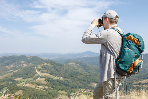 Man looking through binoculars when holding backpack on his back