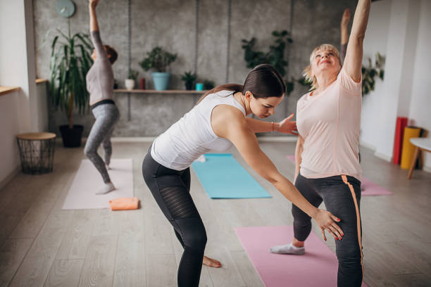 istock Yoga instructor assisting women on yoga class 1300663908