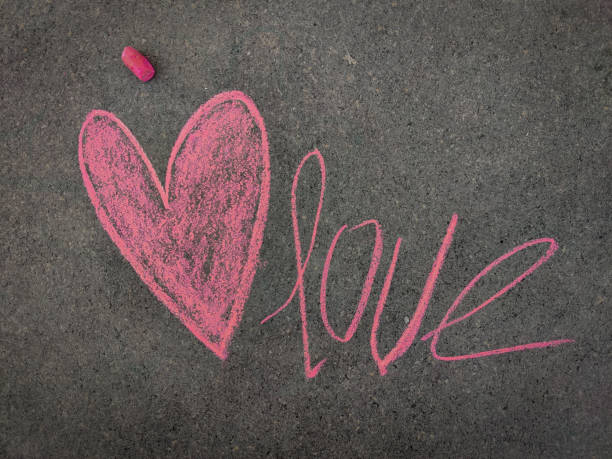 istock Selective focus .The inscription text on the grey board, Love with heart or love symbol. Using color chalk pieces. 1300665480