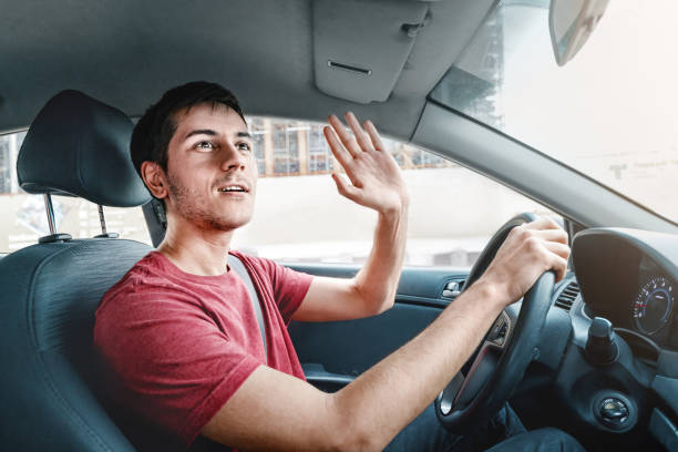 Joyful and careless car driver raises his hand in thanks for giving way. Traffic rules and politeness concept Joyful and careless car driver raises his hand in thanks for giving way. Traffic rules and politeness concept yield sign photos stock pictures, royalty-free photos & images