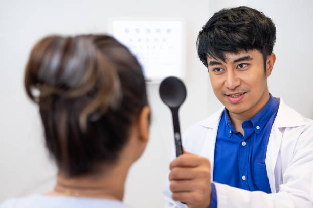 selektywne skupienie na twarzy optometrysty. podczas gdy lekarz za pomocą penlight i subiektywne załamanie do zbadania systemu wzrokowego oczu starszych pacjentek z profesjonalną maszyną przed wykonane okulary. - penlight zdjęcia i obrazy z banku zdjęć