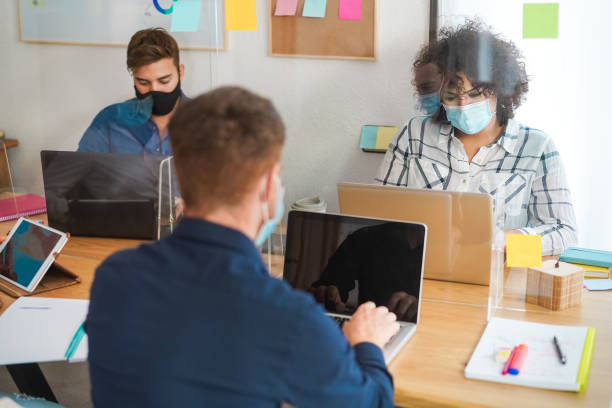 istock Young people working inside modern office behind plexiglas - Focus woman face 1300666687