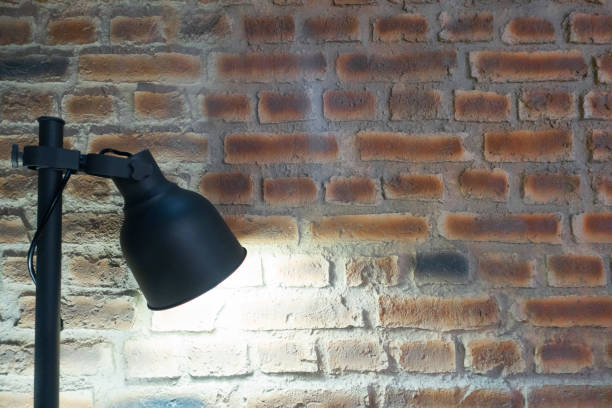 istock Turned on folding reading lamp against red brick wall. 1300669188