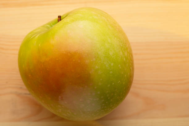 Signle green apple on a wooden background.