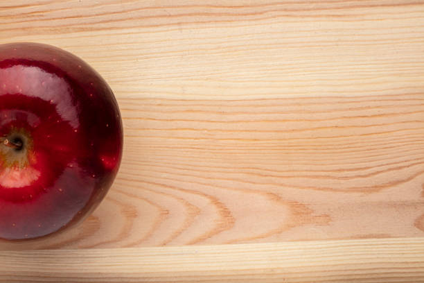 Signle red apple on a wooden background.