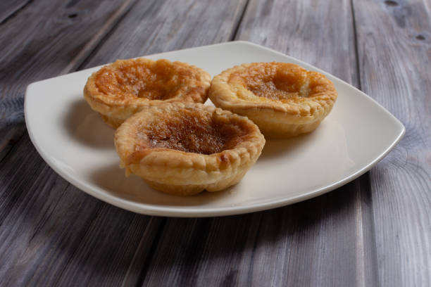 istock Three traditional bakewell puddings on a white plate side view 1300679686