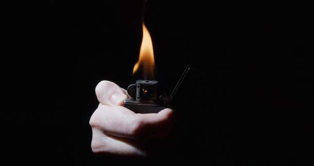 Hand is igniting a cigarette lighter Hand is igniting a cigarette lighter cigarette lighter stock pictures, royalty-free photos & images