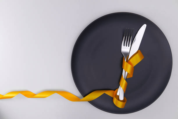 istock Table setting with gray plate and ribbon. Fork and knife for a holiday dinner on a holiday date. Place for taeksta on a white background. 1300685032