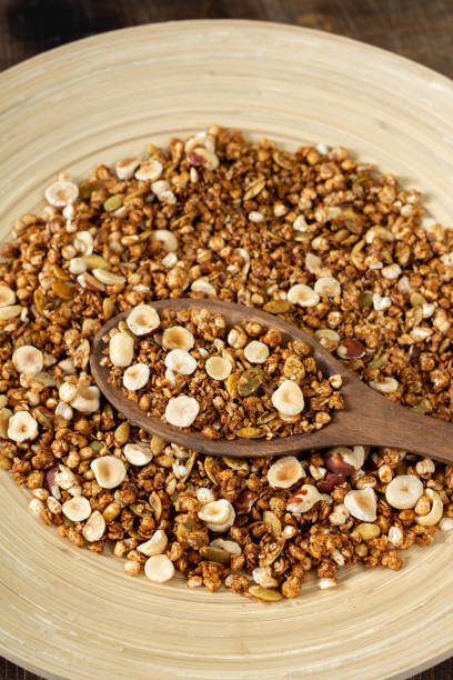 Homemade granola made from buckwheat. Organic buckwheat granola, green buckwheat sprouts, hazelnuts, pumpkin seeds, flax seeds and nutmeg. Granola in a wooden plate on a wooden table. Close-up granola casera hecha de trigo sarraceno. granola de trigo sarraceno orgánico, brotes de trigo sarraceno verde, avellanas, semillas de calabaza, semillas de lino y nuez moscada. granola en un plato de madera sobre una mesa de madera. primer plano