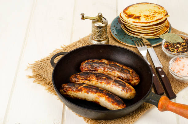 Grilled sausages, pancakes on white wooden table. Studio Photo