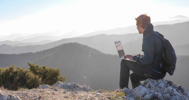 istock Young man uses laptop on mountain on a windy day 1300689770