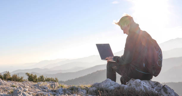 istock Young man uses laptop on mountain on a windy day 1300689794
